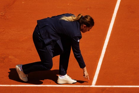 Chair umpire pointing out a mark on clay. 