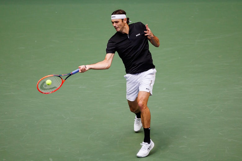 Taylor Fritz hits a forehand in his black and white BOSS outfit.