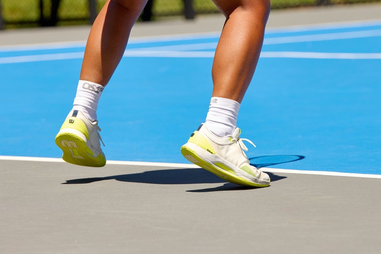 Tennis player split stepping in white/yellow Wilson Intrigue Tour shoes