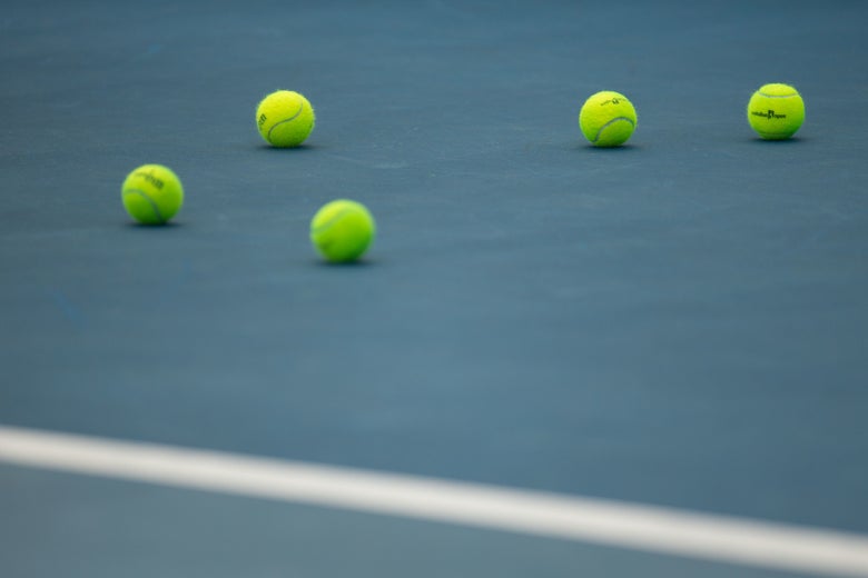 Tennis court with tennis balls on it. 