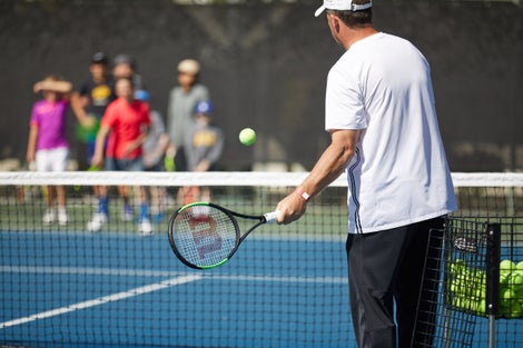 Tennis Pro feeding tennis balls to kids