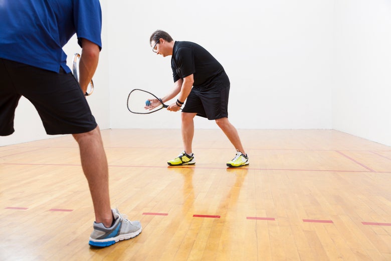 One racquetball player getting ready to serve and another player waiting to return